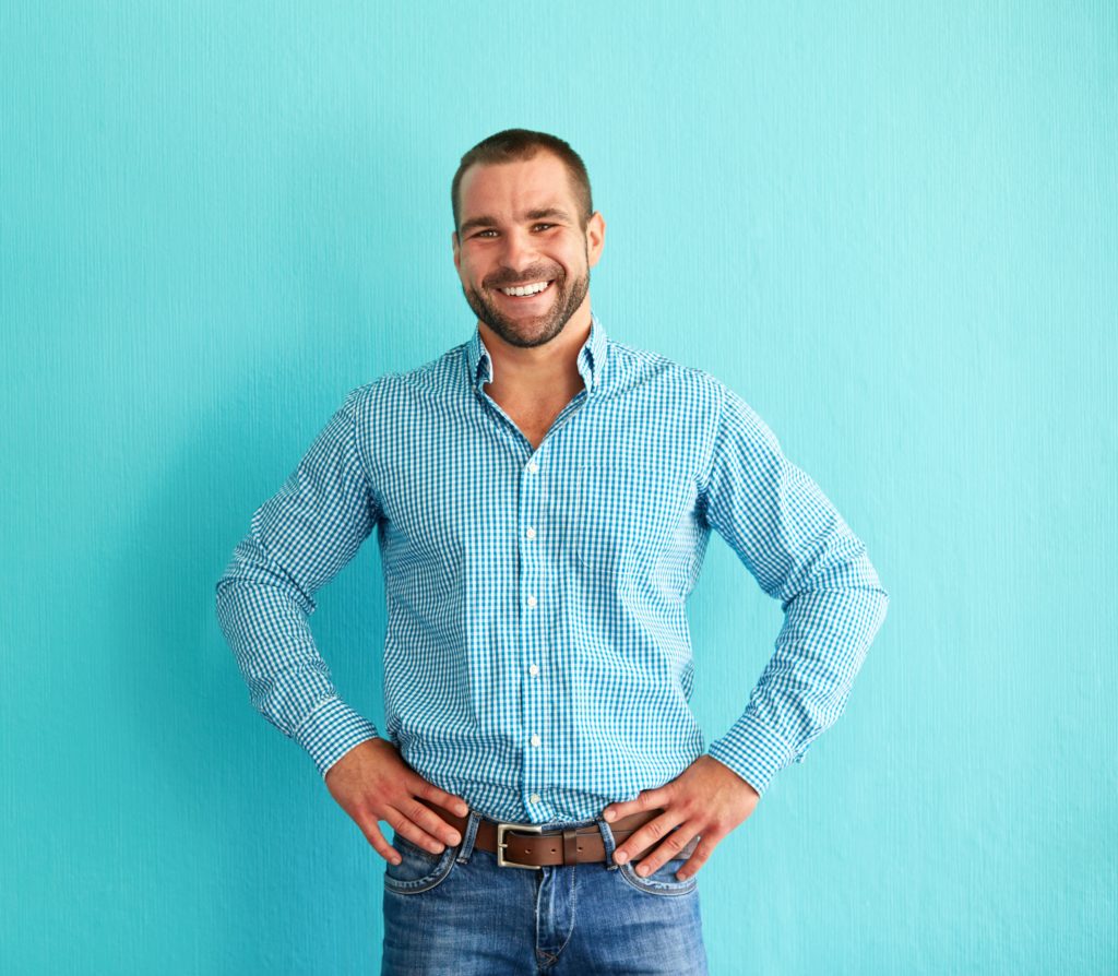 Smiling man standing in front of turquoise wall