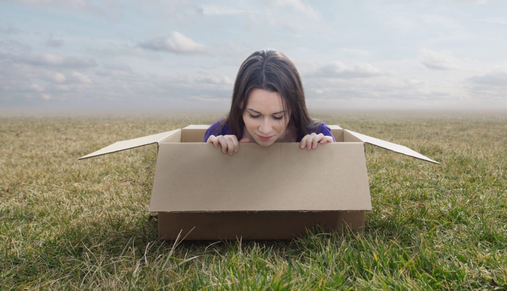 Surreal image of a woman stuck inside a small cardboard box.